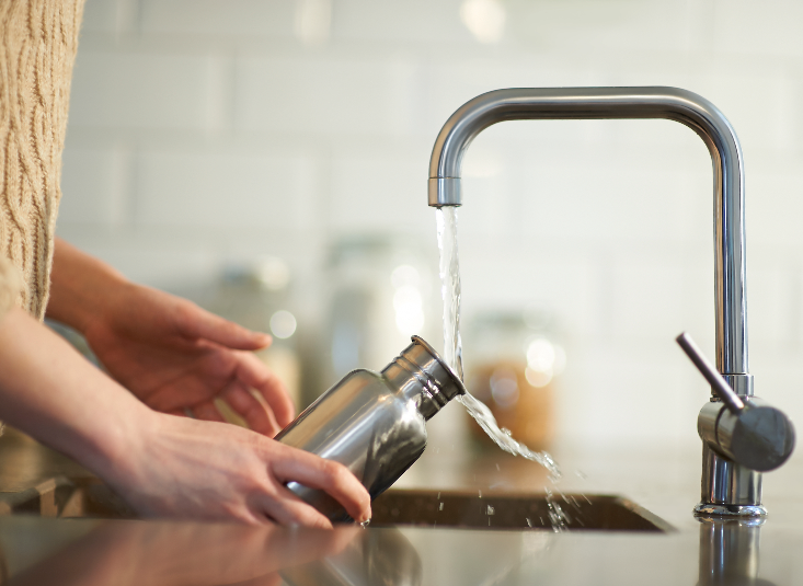 An unseen person fills a reuseable bottle with water from a tap